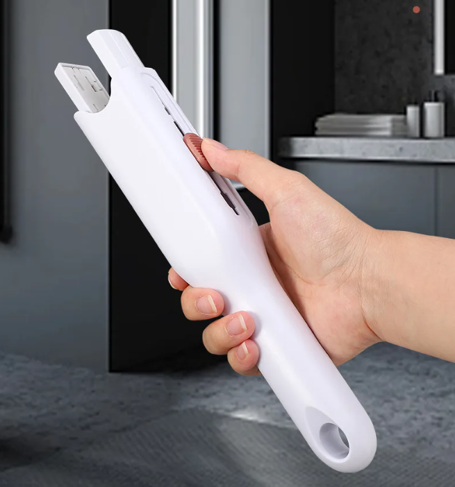 Hand holding a white mini portable cleaning mop in a kitchen setting