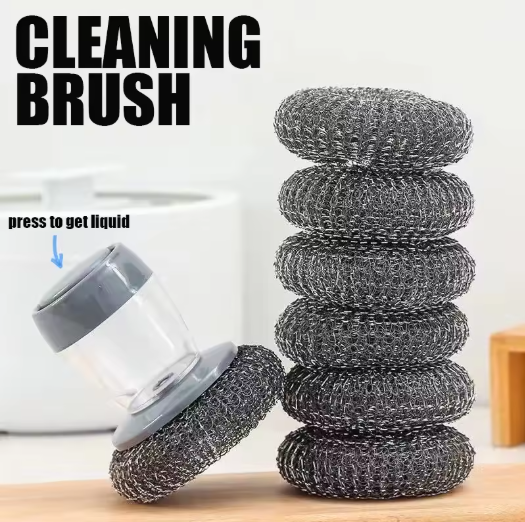 Cleaning brush with liquid container and stacked scrubber pads on a wooden surface.