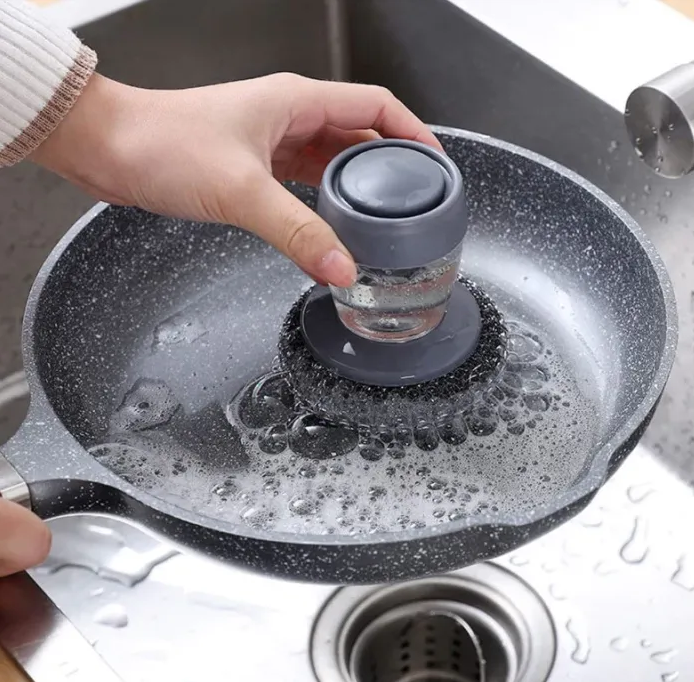 Person using a kitchen soap dispenser steel brush.