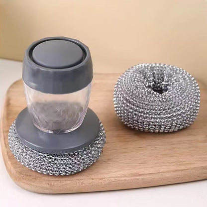 Soap dispenser steel brush with gray lid and base and metallic scrubber on a wooden board.